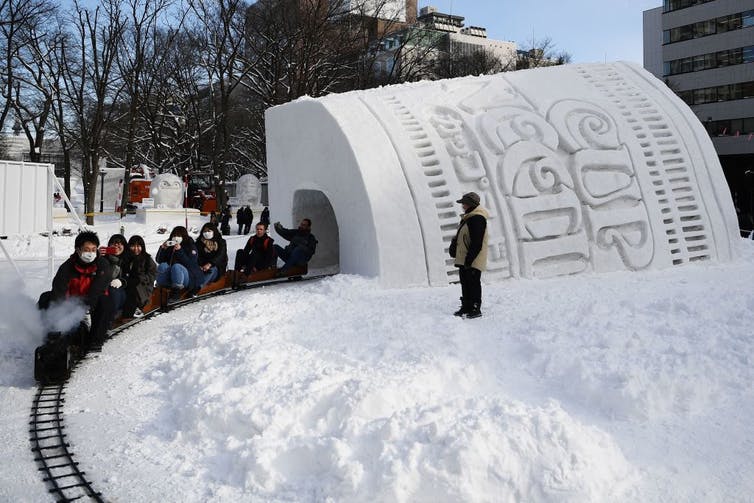Gente que viaja en tren pequeño a través del túnel de nieve.