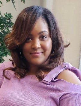 Sarah Holliday, una mujer negra con un top morado, sonríe.