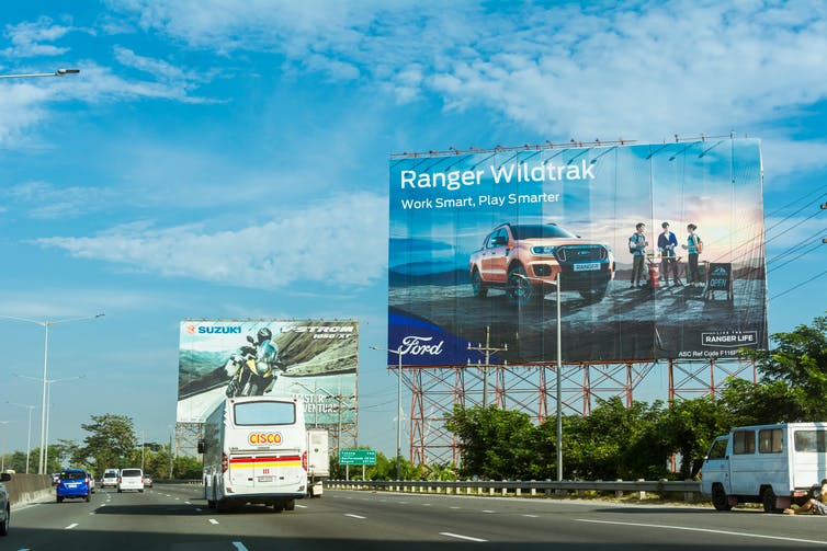 Vallas publicitarias para motocicletas y camionetas se alinean en una autopista.