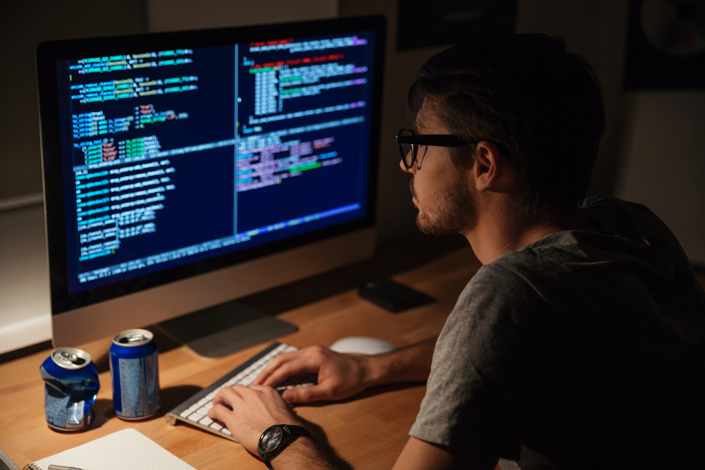 Joven programador pensativo codificando en la computadora por la noche en casa-1